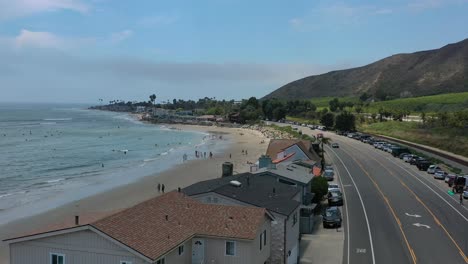 Vista-Aérea-Baja-De-Casas-Frente-Al-Mar-De-Un-Millón-De-Dólares-En-Mondo-Beach-A-Lo-Largo-De-La-Ruta-Uno-De-La-Autopista-De-La-Costa-Del-Pacífico-En-Un-Día-Soleado-De-Verano-Mientras-Los-Turistas-Disfrutan-Del-Surf