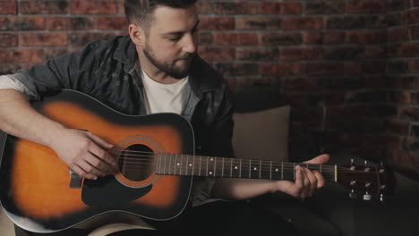 young musician man playing guitar and singing at home