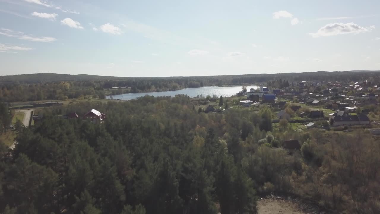 vista aérea de una aldea junto a un lago y un bosque