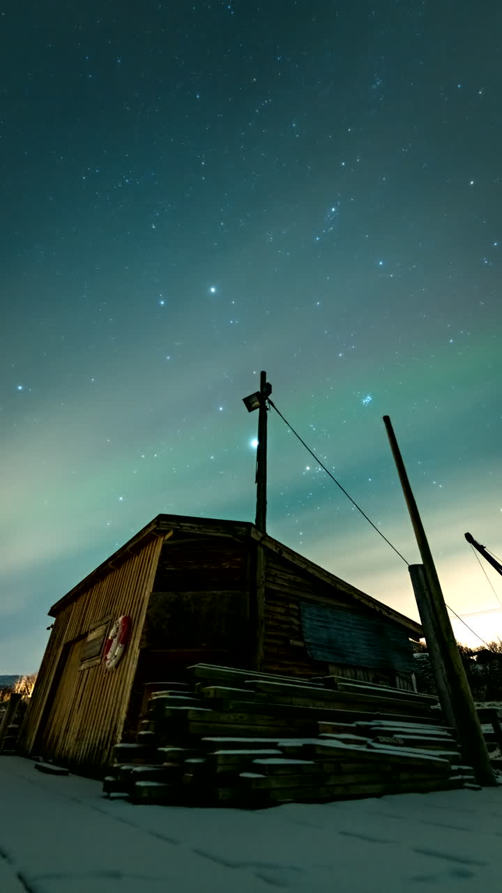 Vertikal time-lapse af nordlys på nattehimlen over et træbådehus