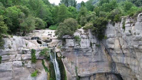 close to pull back reveal aerial view of rocky cliff edge waterfall cascading down rocky steep drop