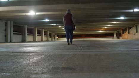 mujer caminando sola por el estacionamiento vacío a altas horas de la noche