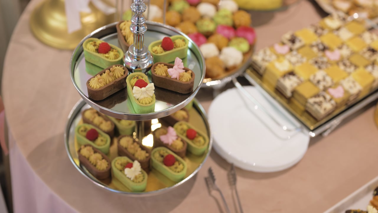 Close-up of an elegant dessert display featuring a tiered serving stand filled with colorful mini pastries and refined sweets.