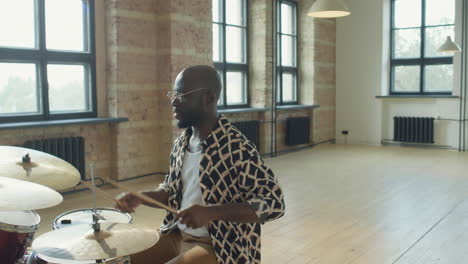 african american drummer talking on camera and playing drums