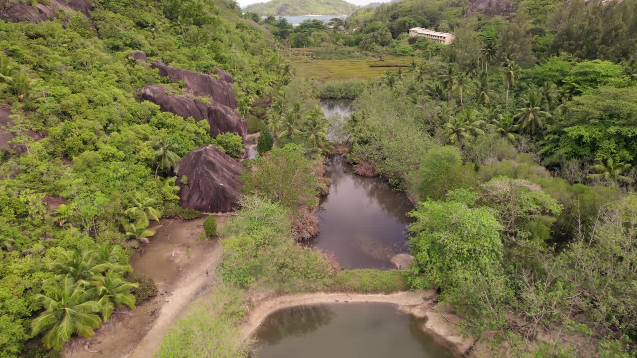 Drone footage of mangrove and lush forest and granites stones at the old NYS school, Cap ternay, Mahe, Seychelles 30fps