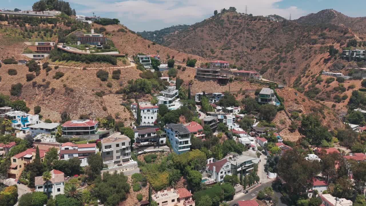 Aerial wide reverse pullback shot of hillside homes in the upscale neighborhood of Hollywood Hills in Los Angeles, California. 4K