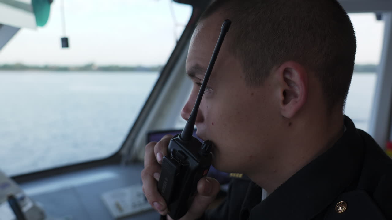 A young man, a ship's officer, communicates or observes from the bridge