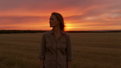 a woman in a field at sunset