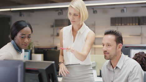 beautiful blonde woman meeting with small business team around touchscreen computer to discuss creative brainstorming late at night