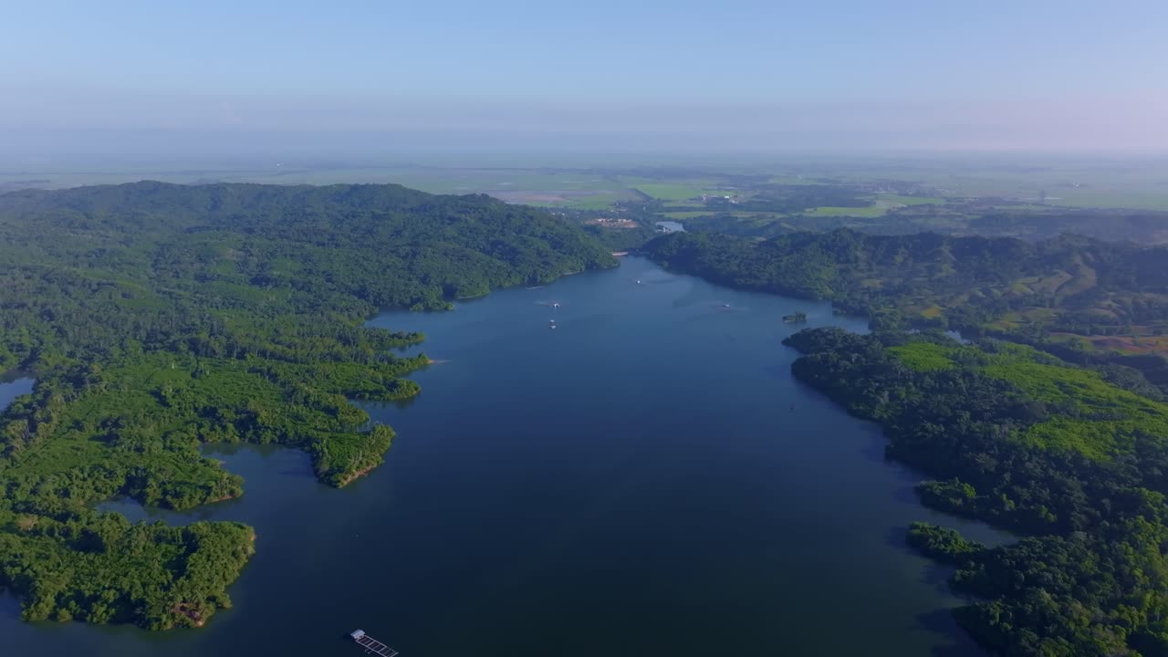 Vast Rincon dam reservoir surrounded by lush green hills and winding shorelines under clear blue sky, Dominican Republic. Perfect for travel and nature content. Aerial forward