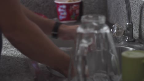 manos masculinas limpiando un plato con esponja y jabón en el fregadero de la cocina - toma estática