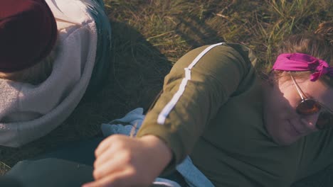 joyful women rest frolicking on grass at camp in evening