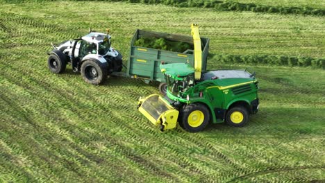 Aerial-Tracking-Shot-Of-Freshly-Cut-Silage-Being-Offloaded-Onto-A-Truck-And-Then-Leaving