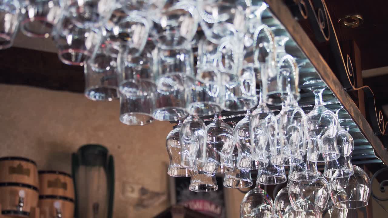 Clean washed and polished glasses for wine hanging over a bar rack. Empty wine glasses in the restaurant