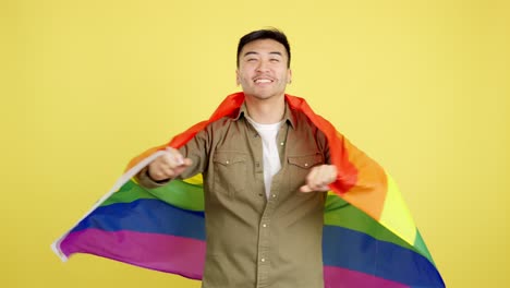 smiling man wrapped in a rainbow flag on a yellow background
