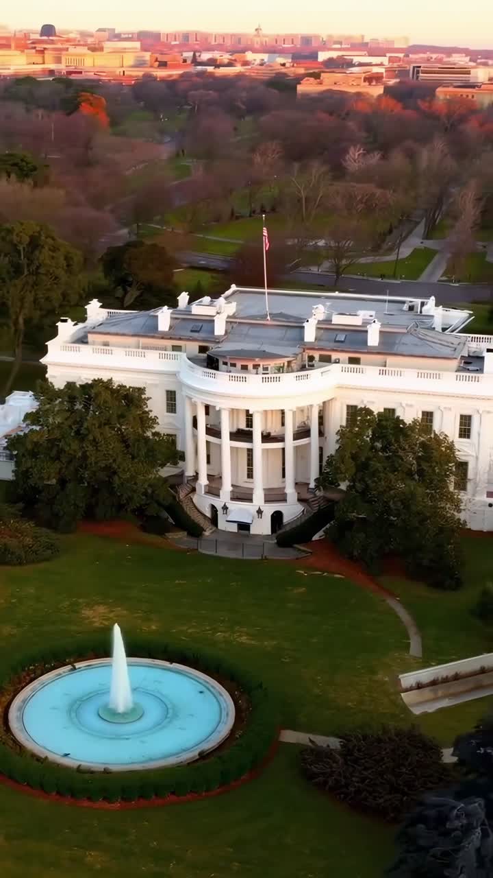 Video aereo di un grande edificio bianco con una fontana, ripreso al tramonto, che mostra vasti giardini