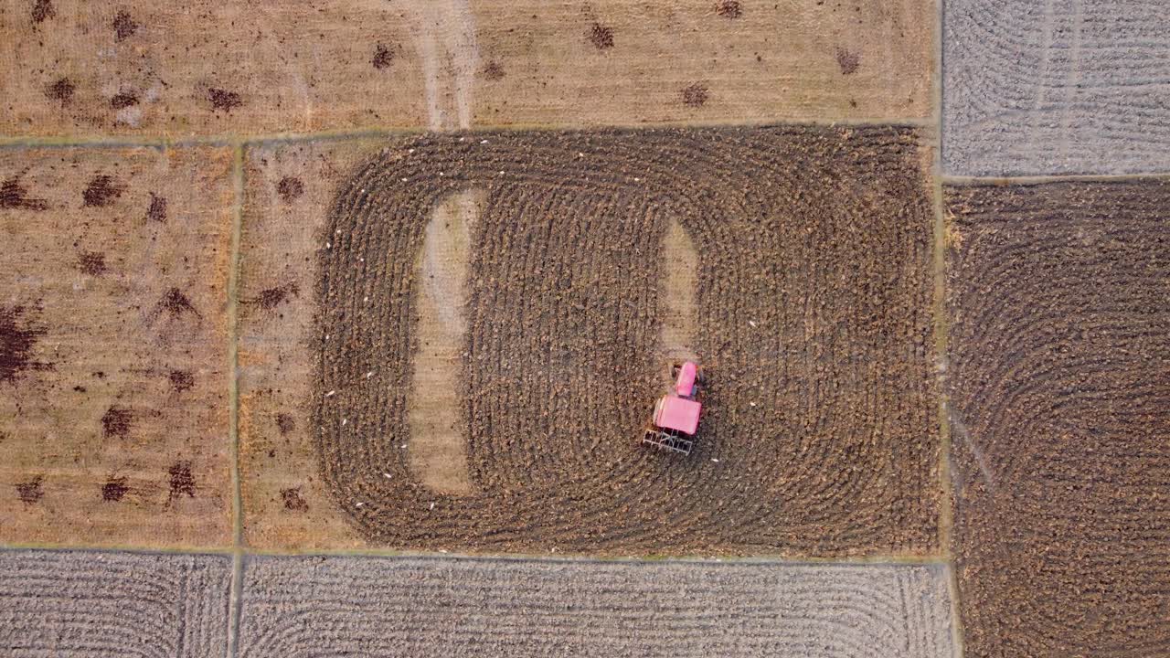 An agricultural tractor ploughing soil at large potato farm fields, West Bengal rural village farmland, Top view, Aerial