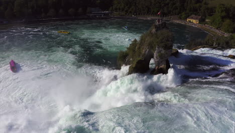toma de seguimiento de una roca sentada en la cascada rugiente rheinfall en schaffhausen en suiza