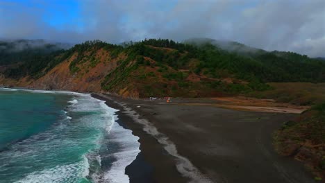 sunny clear blue skies misty rugged surf rocky mountainside cliffs bluffs untouched remote usal beach campground california aerial drone camping sinkyone wilderness lost coast trail forward up motion