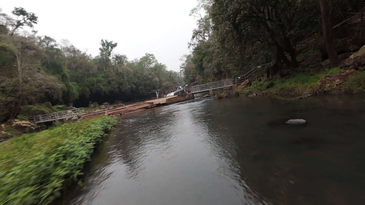 Aerial footage capturing a river meandering through the lush, dense forest of Misiones, Argentina, revealing the breathtaking natural beauty of Gruta Indias serene landscape