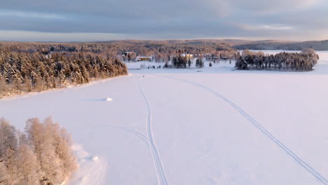 aerial view of a snowmobile driving on ice, cold, winter morning in snowy finland