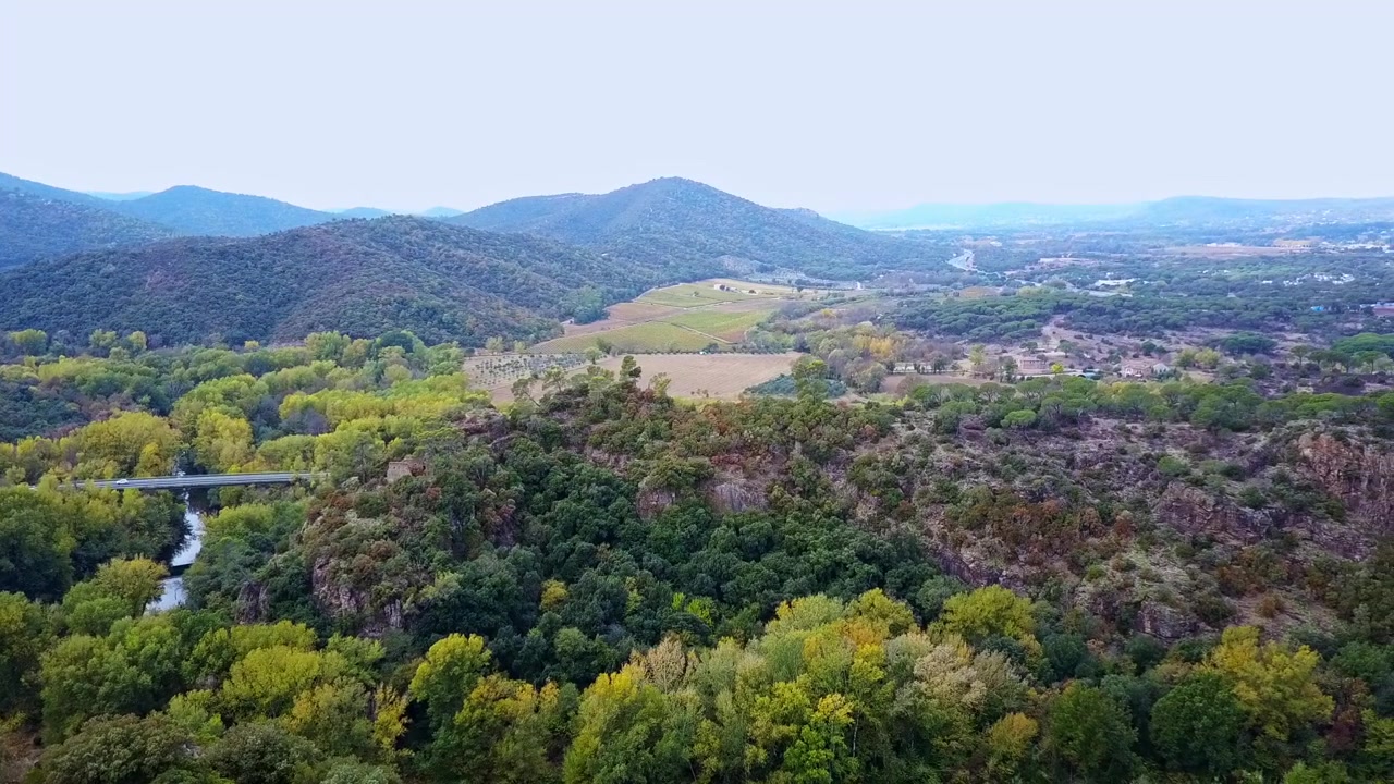 Ripresa aerea con panoramica a destra di un ponte nella foresta, alcune case con una valle/canyon sottostante, Francia del Sud