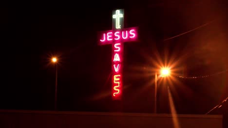 a handheld night shot of a neon sign which reads jesus saves