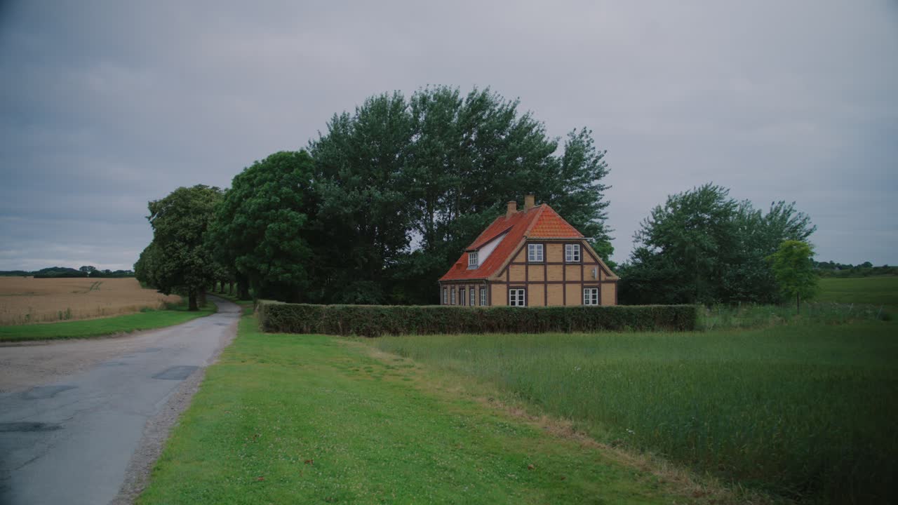 House on a rural road in Langeland, Denmark, surrounded by lush green trees and fields