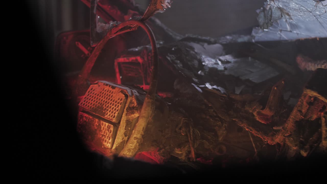 Detailed slow motion close-up inside a completely charred vehicle at night