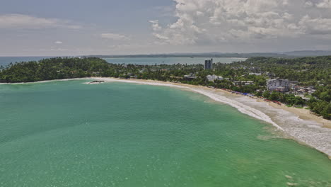 mirissa sri lanka aerial v2 flyover bay capturing turquoise sea water, pristine long sandy beach, beachfront resort hotels and udupila landscape views in summer - shot with mavic 3 cine - april 2023