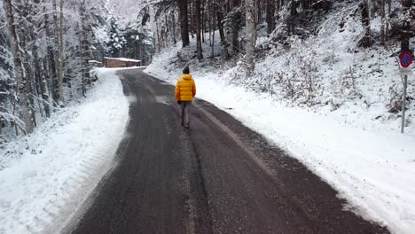 persona caminando por un camino forestal en un bosque de nieve invernal, seguimiento aéreo