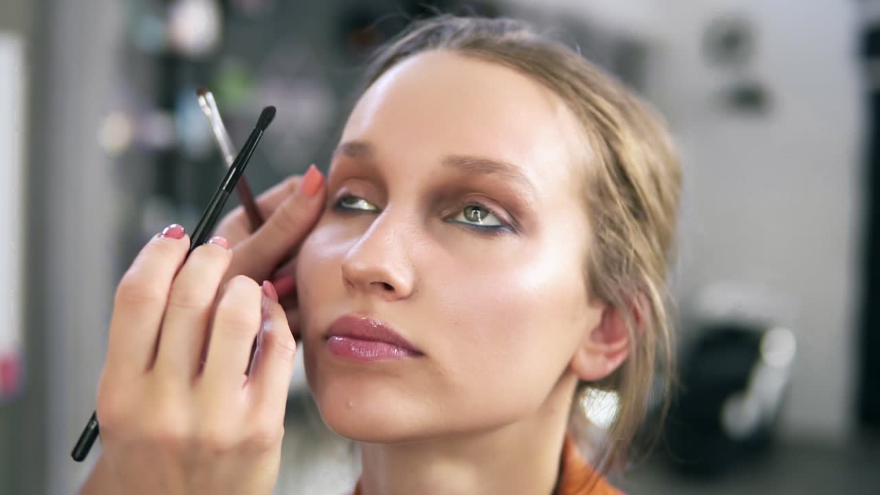estudio de maquillaje. artista de maquillaje profesional haciendo maquillaje para una hermosa modelo caucásica. aplicando algunas sombras de ojos usando una