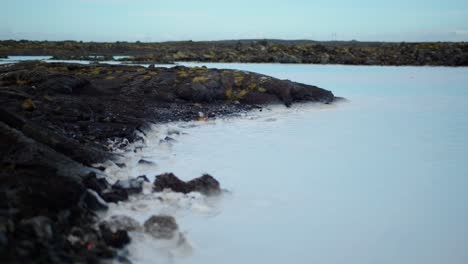Agua-Azul,-Lechosa-Y-Cálida-De-Las-Lagunas-Azules-En-Islandia-Entre-Rocas-Negras