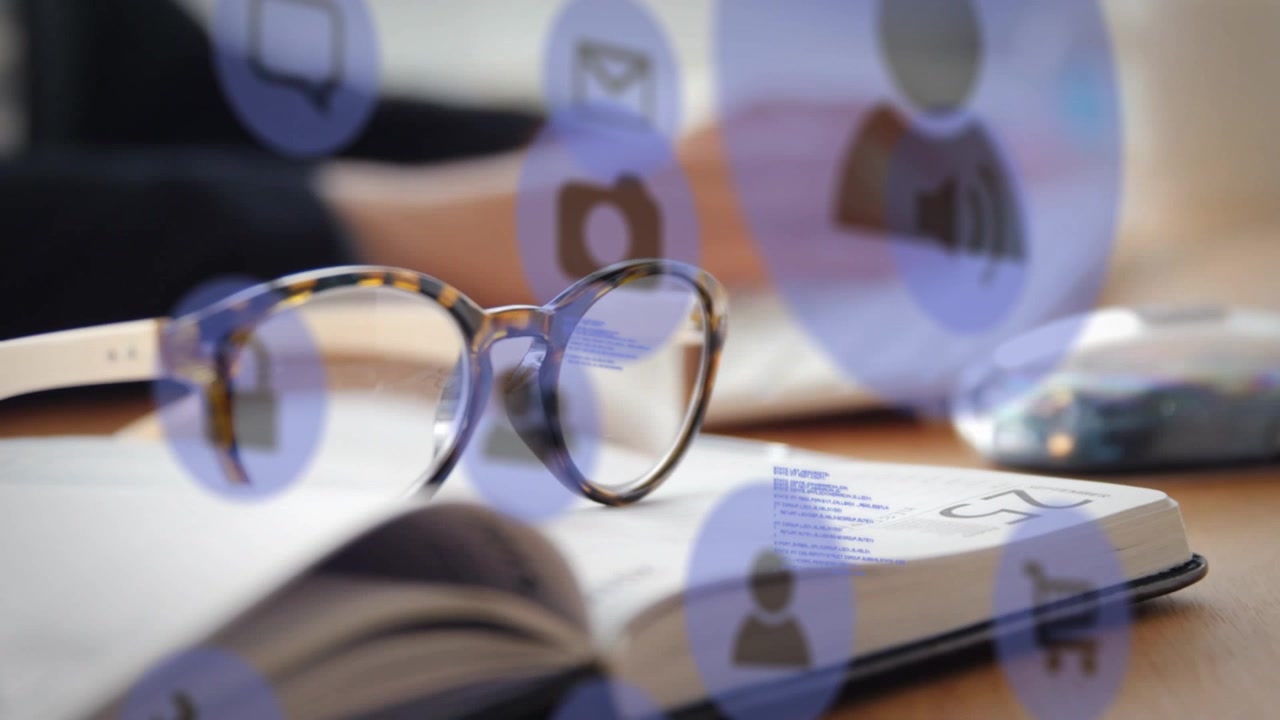 Animation of technology icons over, book, glasses and hands of caucasian man typing on keyboard