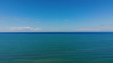 blue turquoise sea horizon bordered by white clouds and bright sky, beautiful background in mediterranean coastline