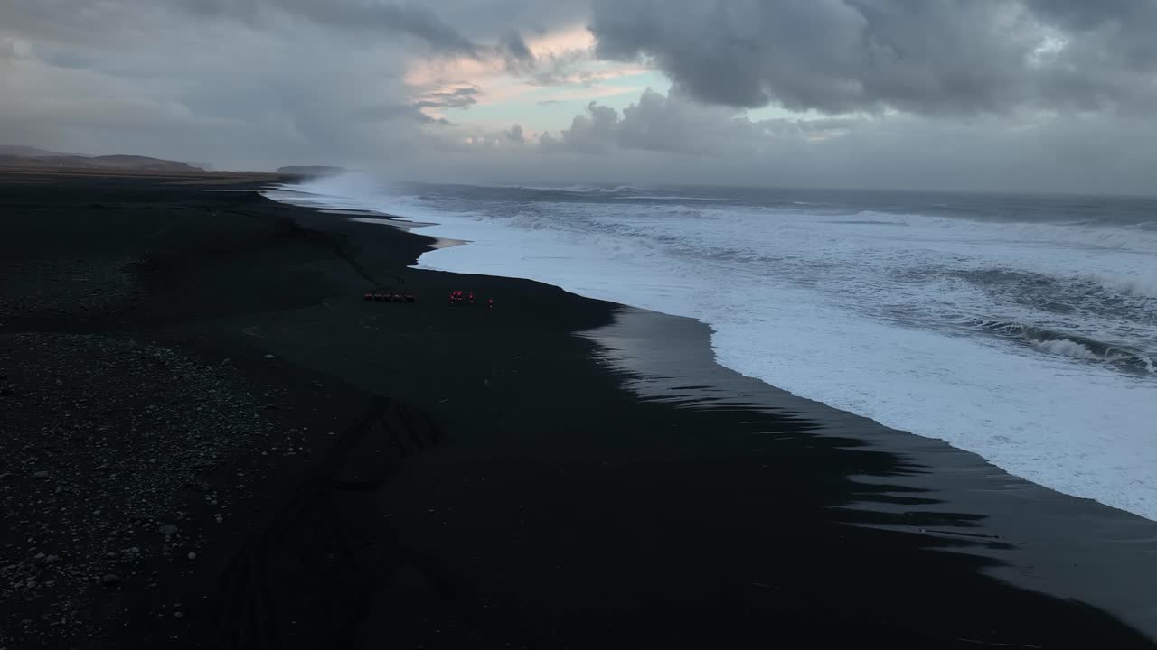 Aerial view of bright red quad bikes on Iceland S&oacute;lheimasandur beach black sand, next to the ocean, at sunset