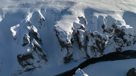 vista panorámica aérea sobre un río glaciar que fluye a través de un cañón cubierto de nieve, en un día soleado