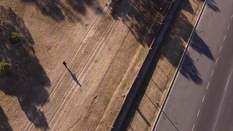 A-dynamic-top-down-aerial-shot-of-a-walking-woman-across-the-La-Plata-Park-in-Buenos-Aires,-Argentina