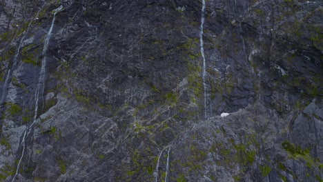 El-Tranquilo-Ascenso-Sobre-Acantilados-Rocosos-Y-Cascadas-Revelan-Picos-Nevados-En-Fiordland,-Nueva-Zelanda,-Isla-Del-Sur.