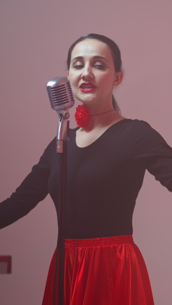 vocalista en un vestido negro y rojo actúa apasionadamente con la mano de un guitarrista borroso tocando una guitarra roja en el fondo, creando una escena musical dinámica