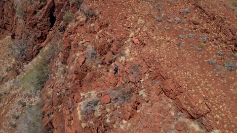 Orbit-Shot-Of-Person-Climbing-Edge-Of-Cliff-In-Hiking-Discovery-Trip,-Western-Australia-Desert
