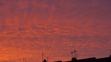 low angle view of moving colorful clouds and silhouette of roofs