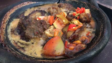 indonesian traditional food beef meat on a hot clay plate with tomato and chilli