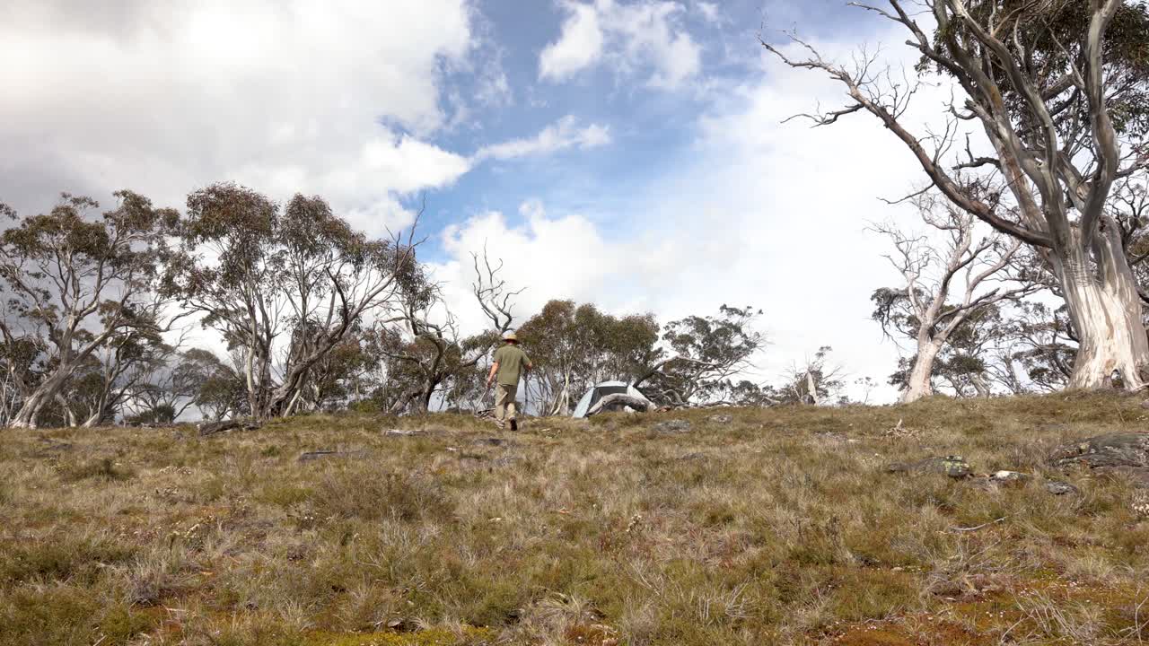 un bosquimano caminando por su campamento alpino en el alto país victoriano