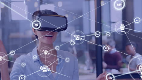animation of network of connections with icons over caucasian businesswoman using vr headset