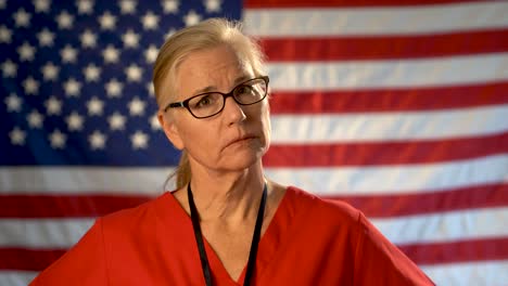 medium tight portrait of a healthcare nurse looking concerned and sympathetic with an out of focus american flag