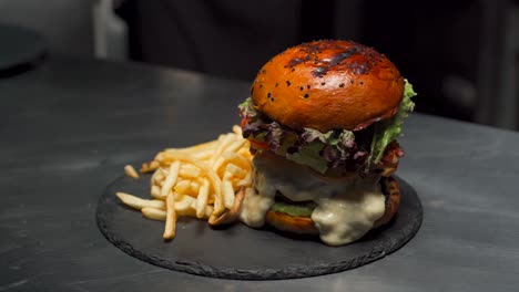 en el chef restaurante gourmet terminar la hamburguesa de queso carne de primera elección añadir pimentón horno patatas fritas brioche pan de semilla de sésamo queso derretido