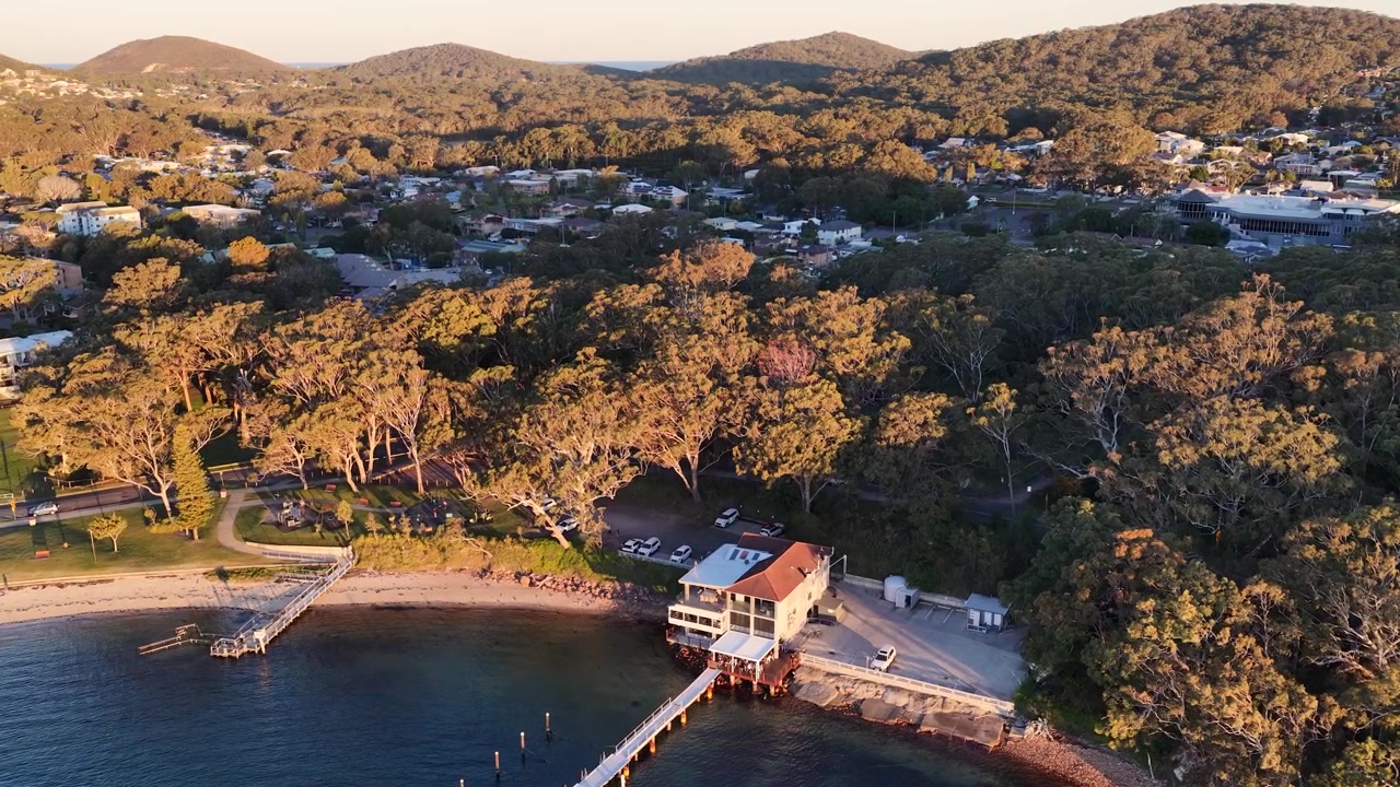 Ripresa drone dall'alto di una località costiera e un pontile durante l'ora d'oro a Nelson Bay