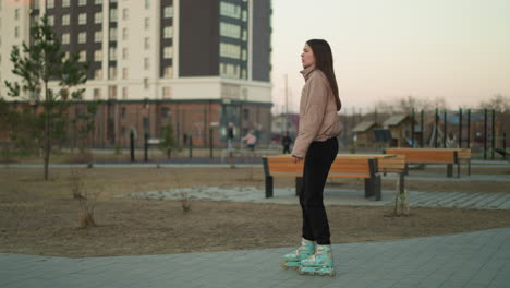 a young girl, dressed in a peach jacket and black trousers, is captured rollerblading along a paved path in a park. the background features benches and a serene park setting