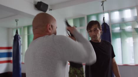 caucasian man learning self defense from trainer in gym